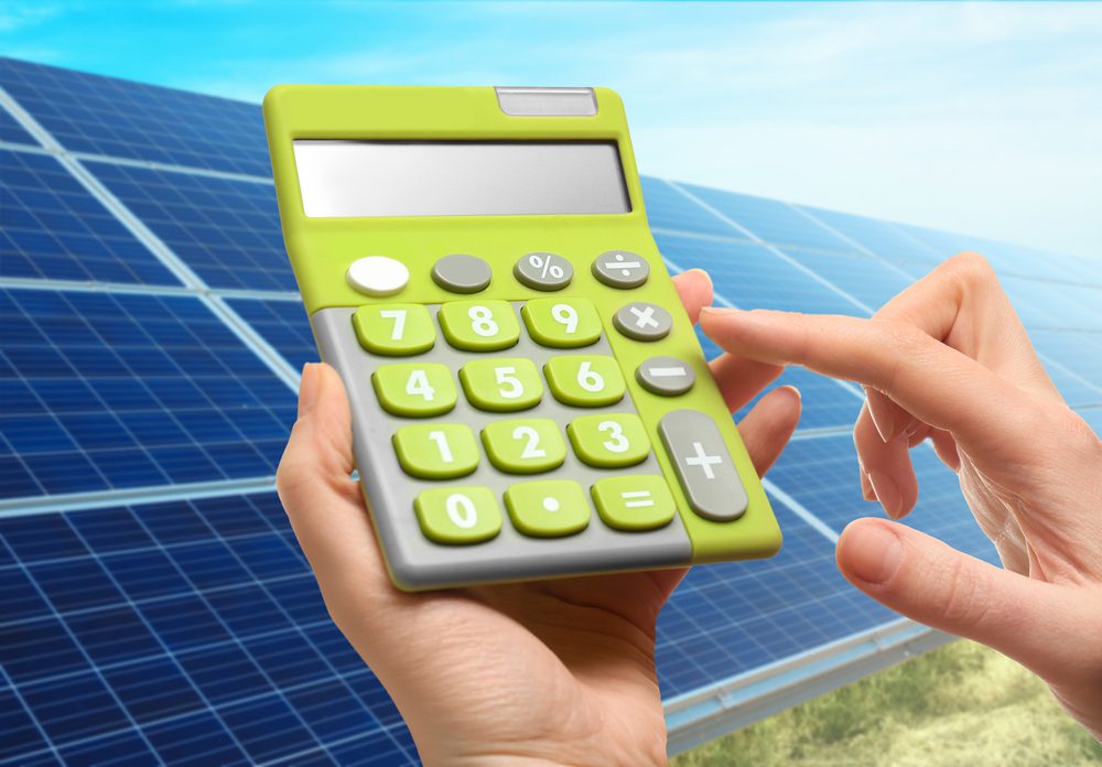 Green calculator in front of solar panels