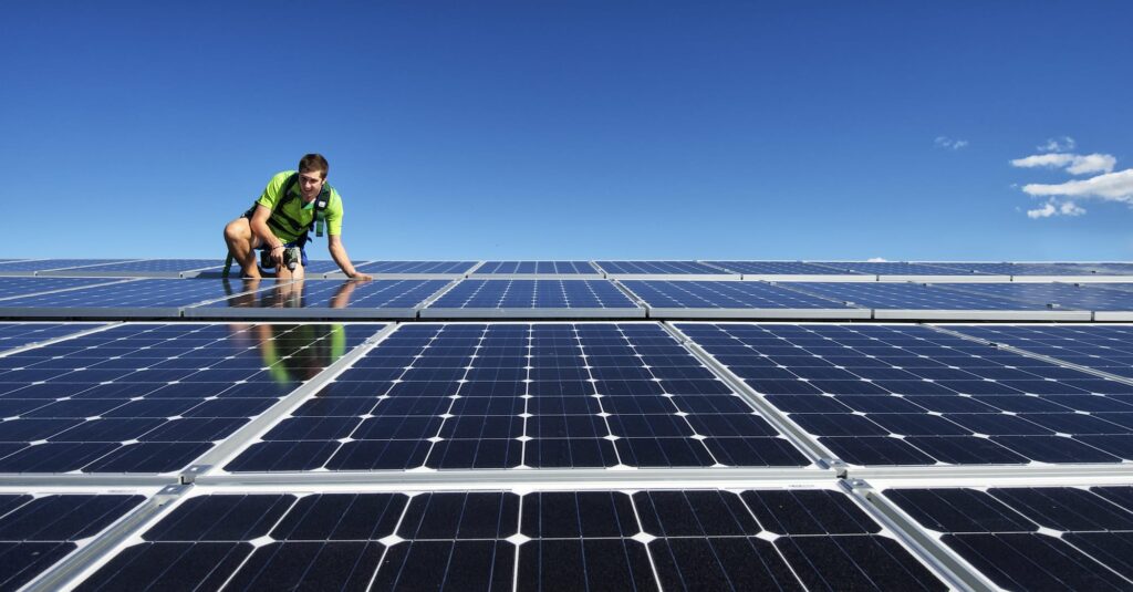 Solar installer on the roof mounting solar panels for renewable energy installation
