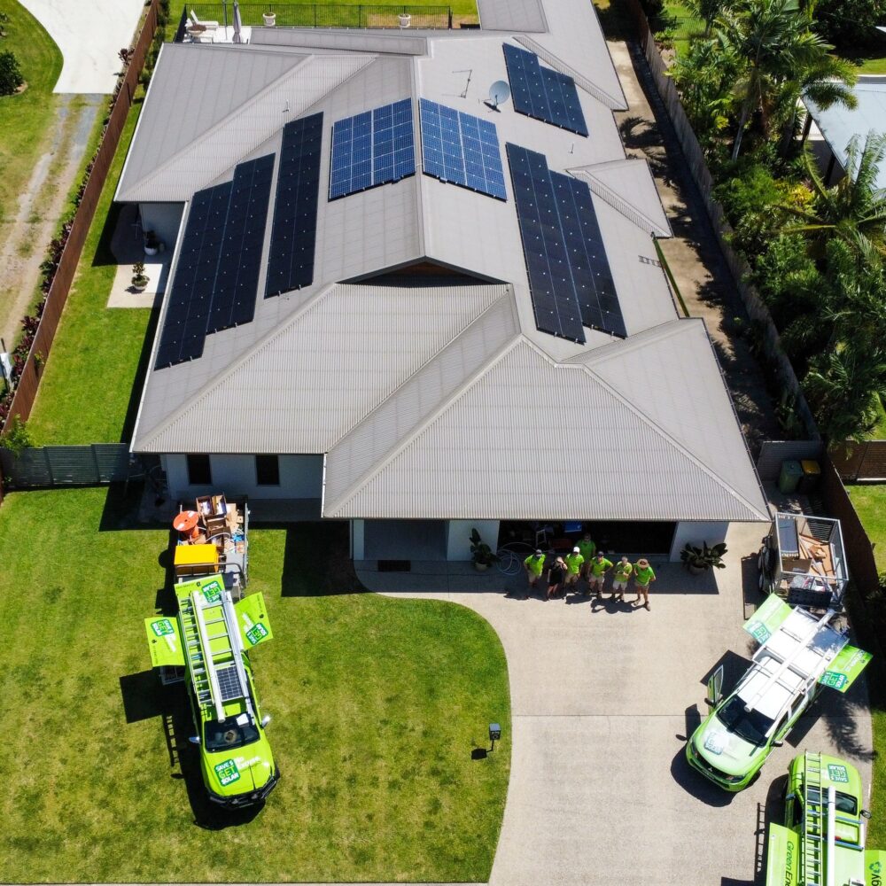 Green Energy Technologies Drone Shot of a group of staff standing in front of a house with solar panels Green Energy Technologies Drone Shot of a group of staff standing in front of a house with solar panels