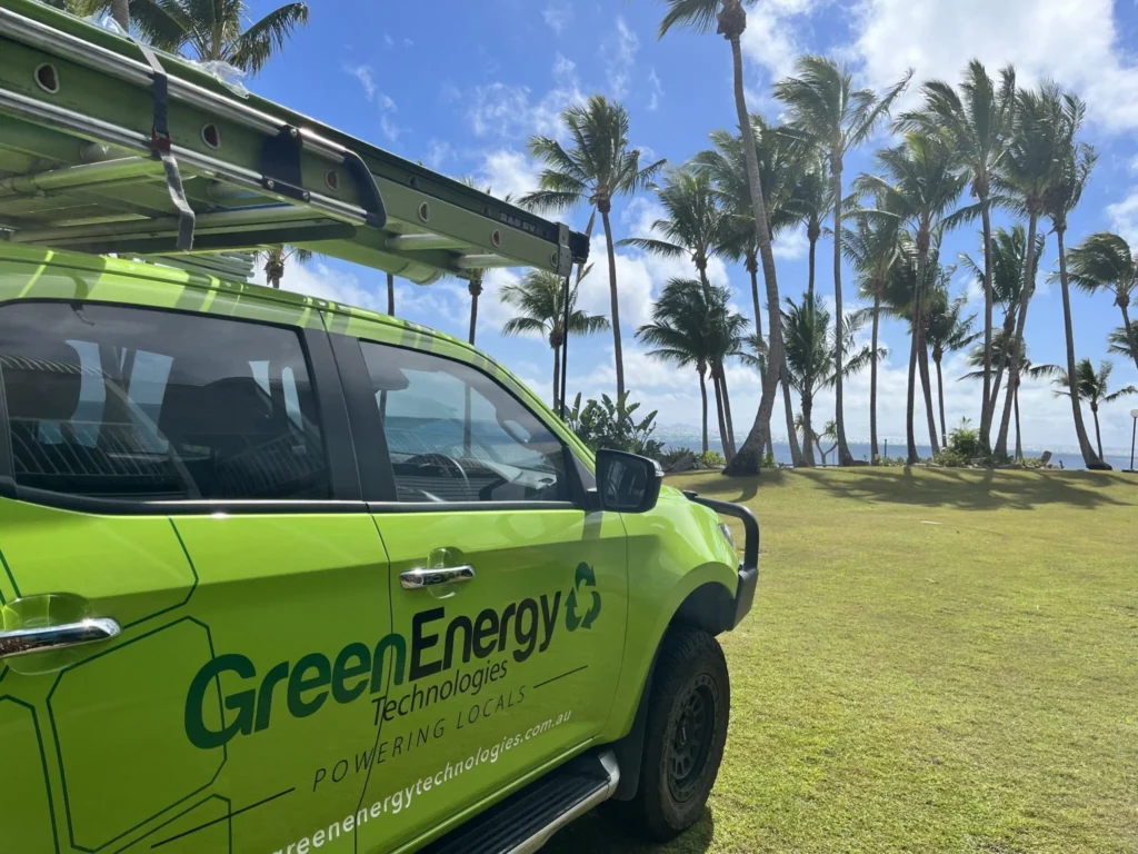 Green Energy Technologies service vehicle parked near a tropical coastline, delivering sustainable solar panel solutions to local communities